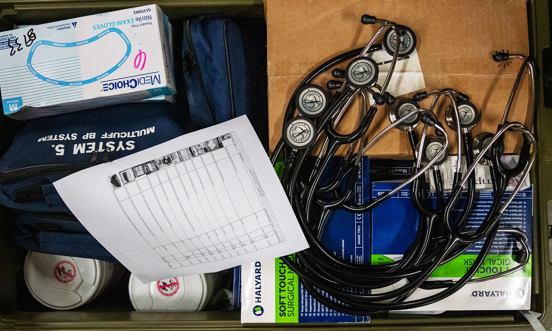 Several stethoscopes are seen as part of a medical kit
