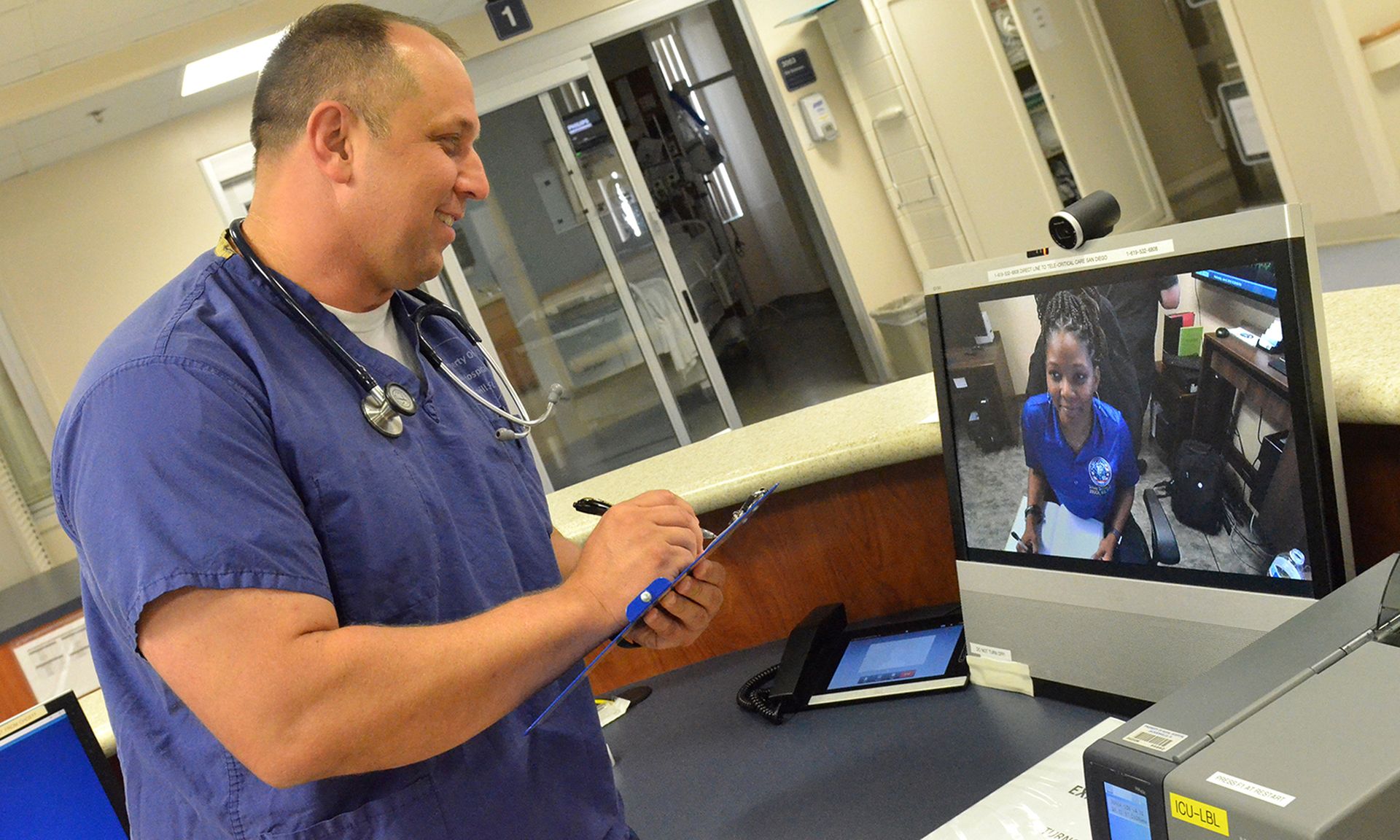 A nurse speaks with a nurse at a different hospital using telehealth equipment.