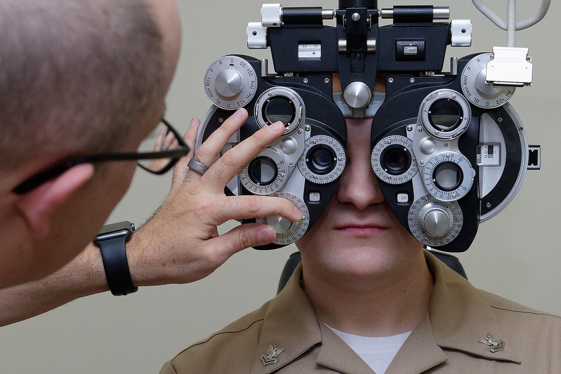An eye exam is performed in a medical office on a Navy sailor.
