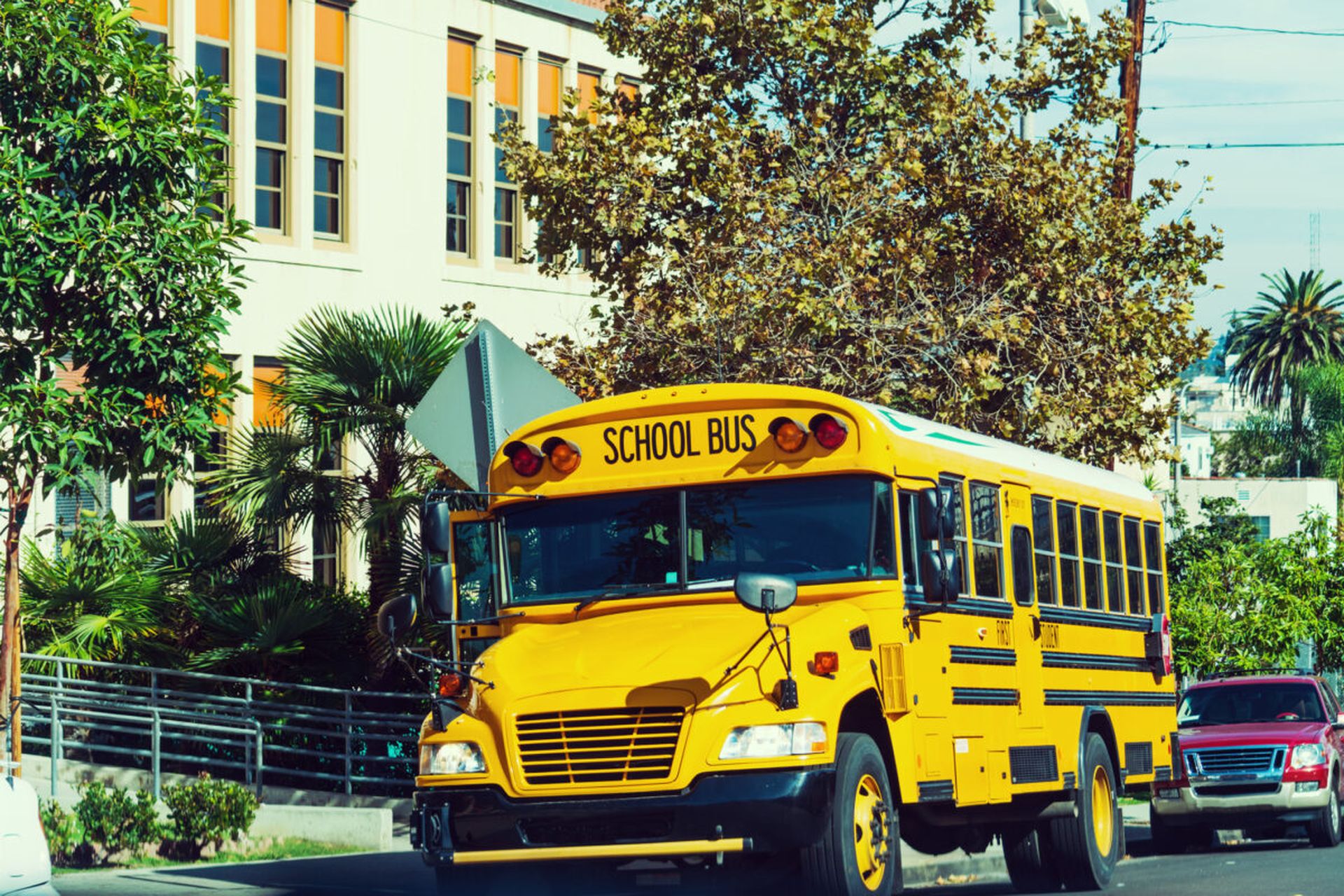 A yellow school bus is parked by a school in Los Angeles.