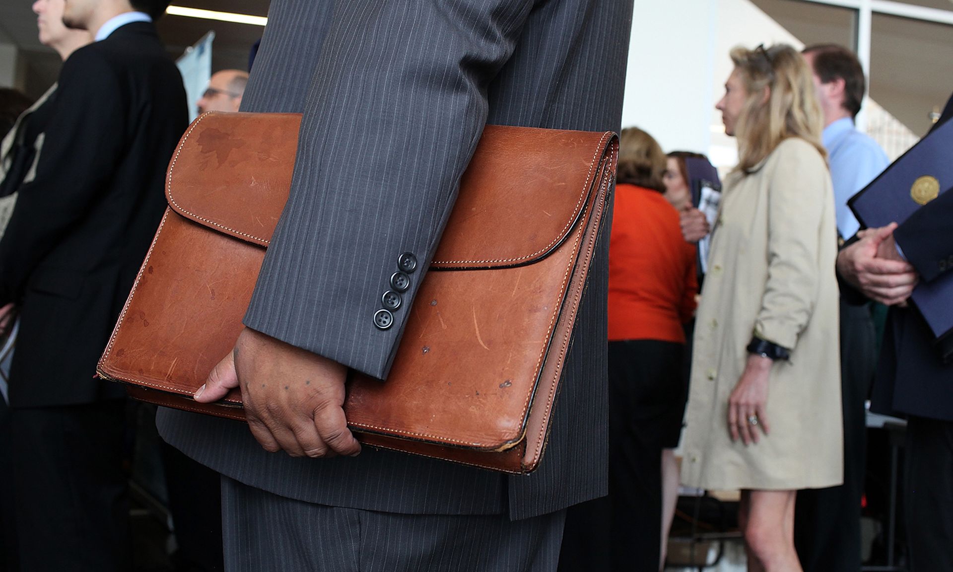 A job seeker holds a briefcase as he waits in line.