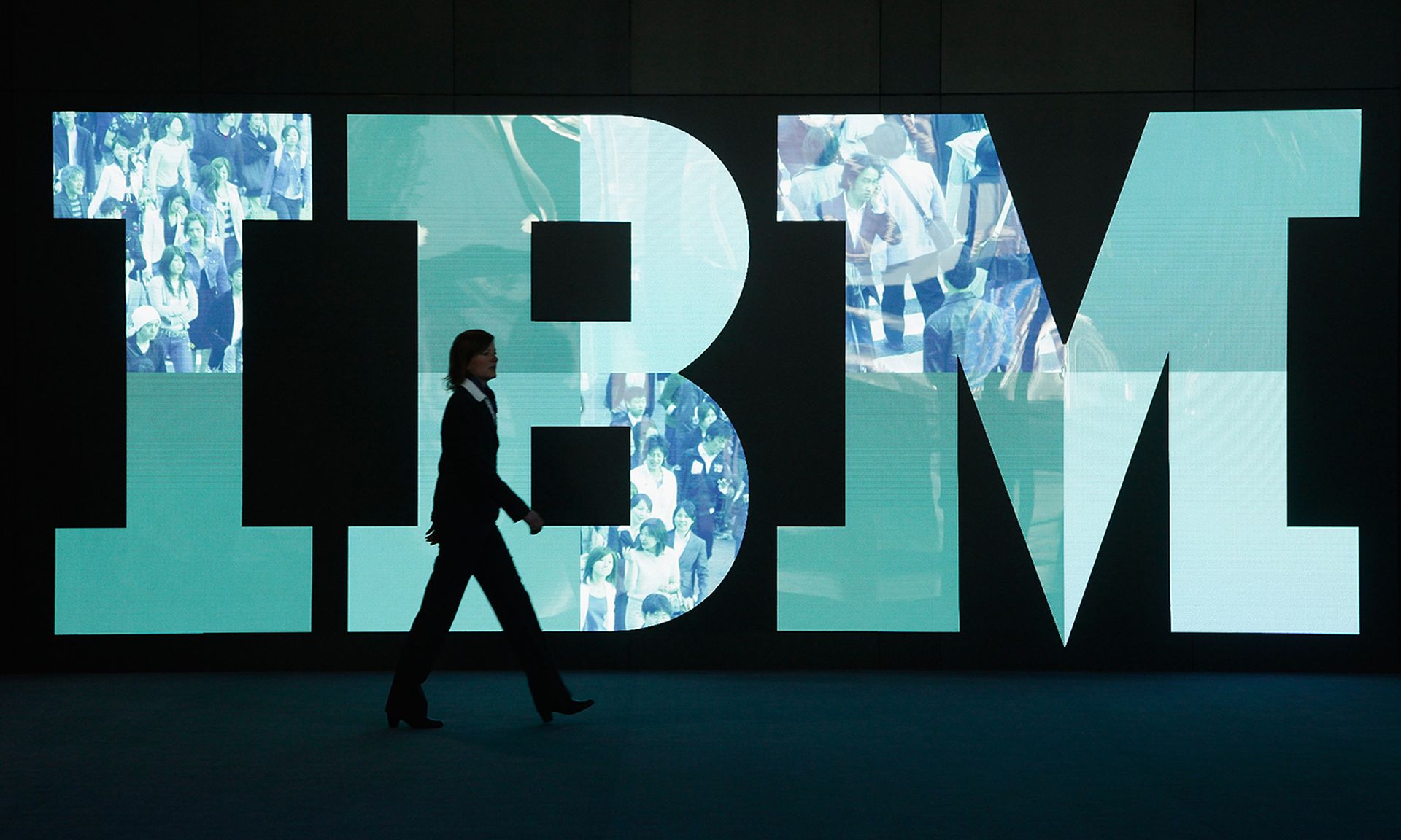 A woman walks past the IBM logo at a technology trade fair.