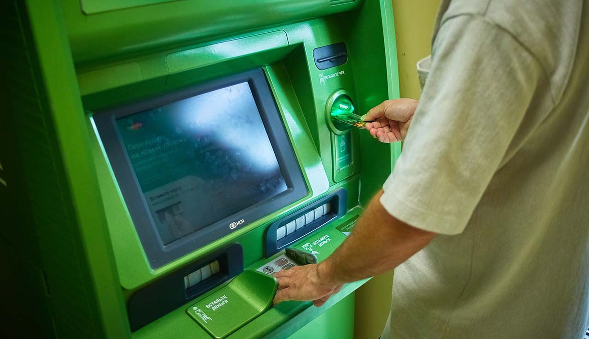 A man uses a green-colored ATM