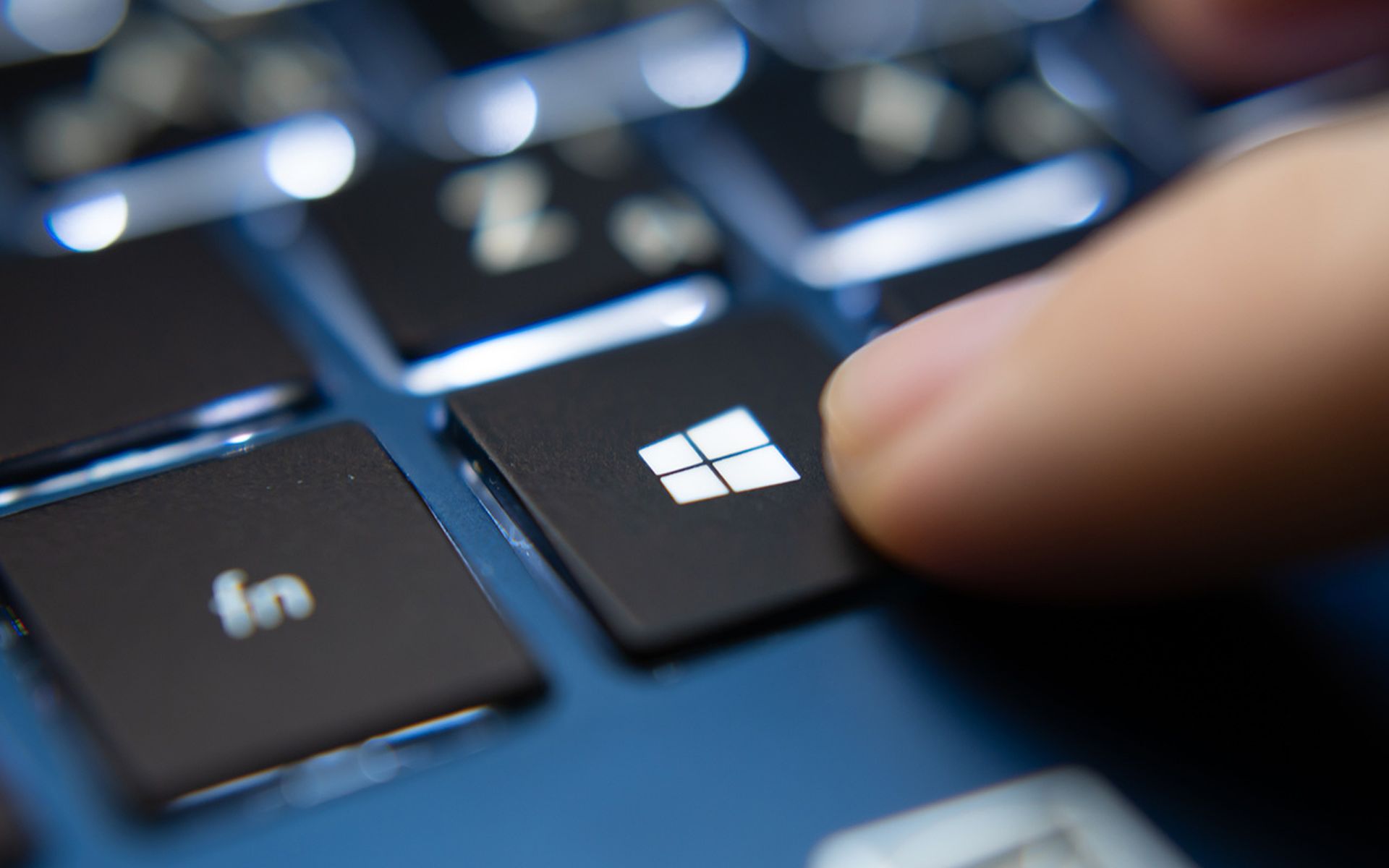 Laptop user pressing Windows Key on Microsoft Windows keyboard.