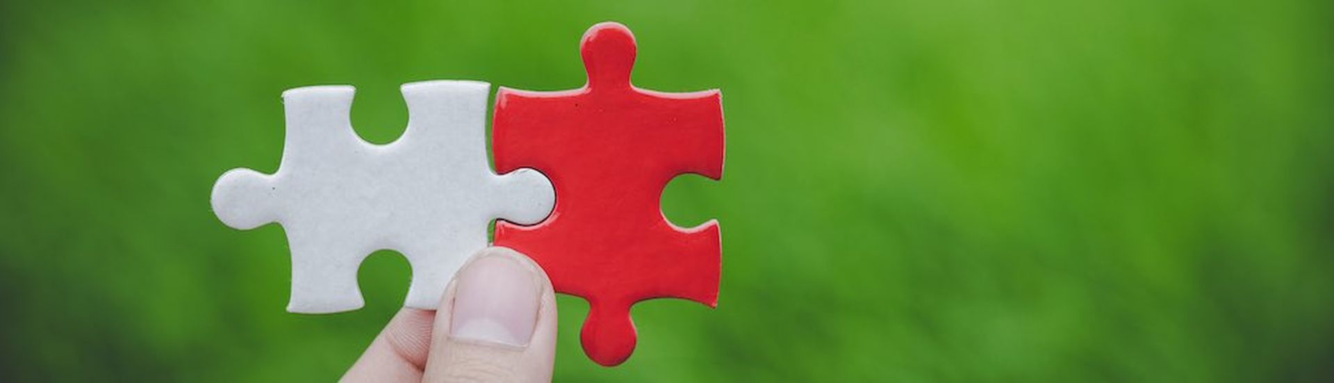 Businessmen join hands in pieces of white and red jigsaw puzzles, teamwork concepts, business solutions, success concepts and strategies, links and connections.