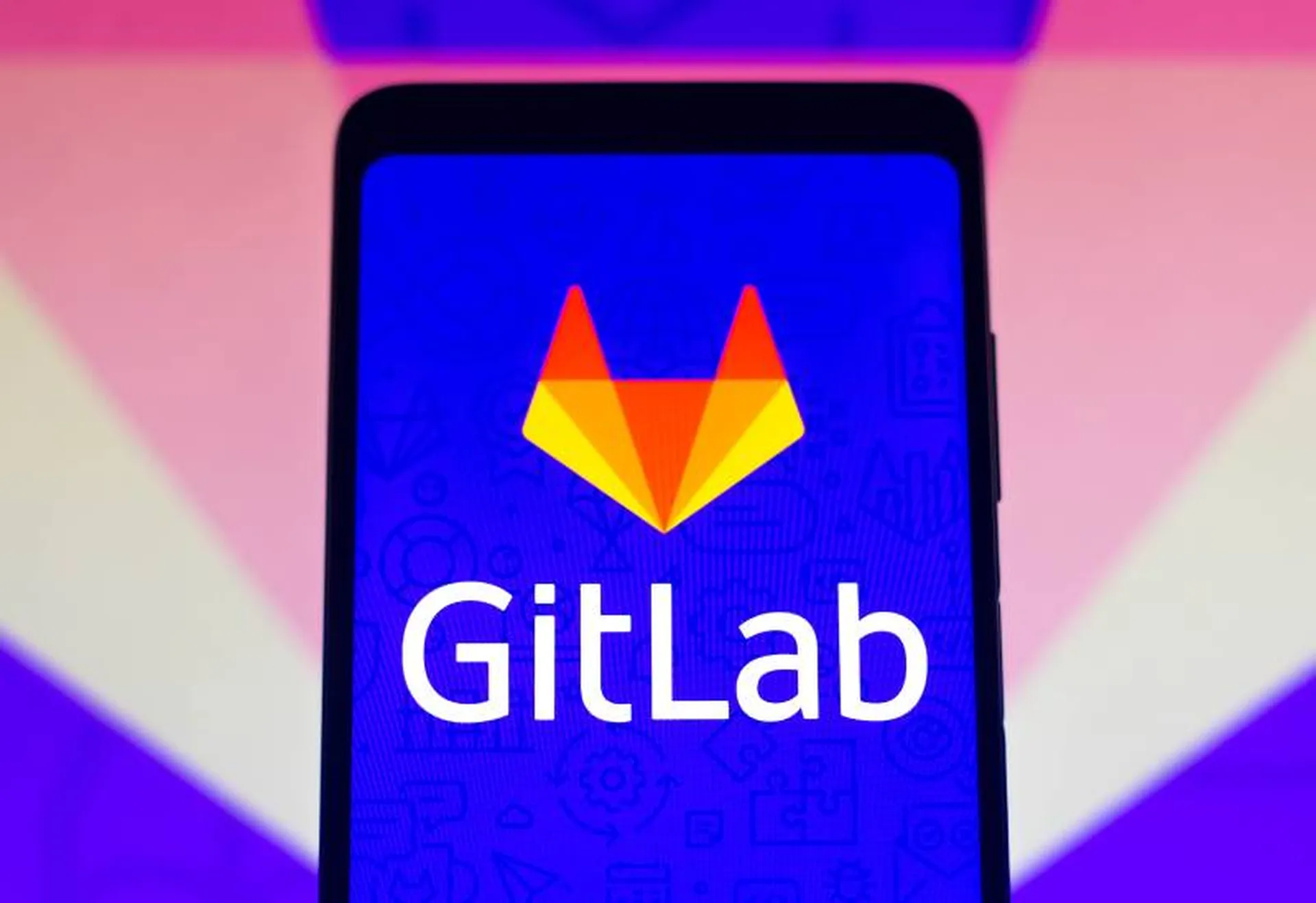In this photo illustration the GitLab logo seen displayed on a smartphone and on the background.