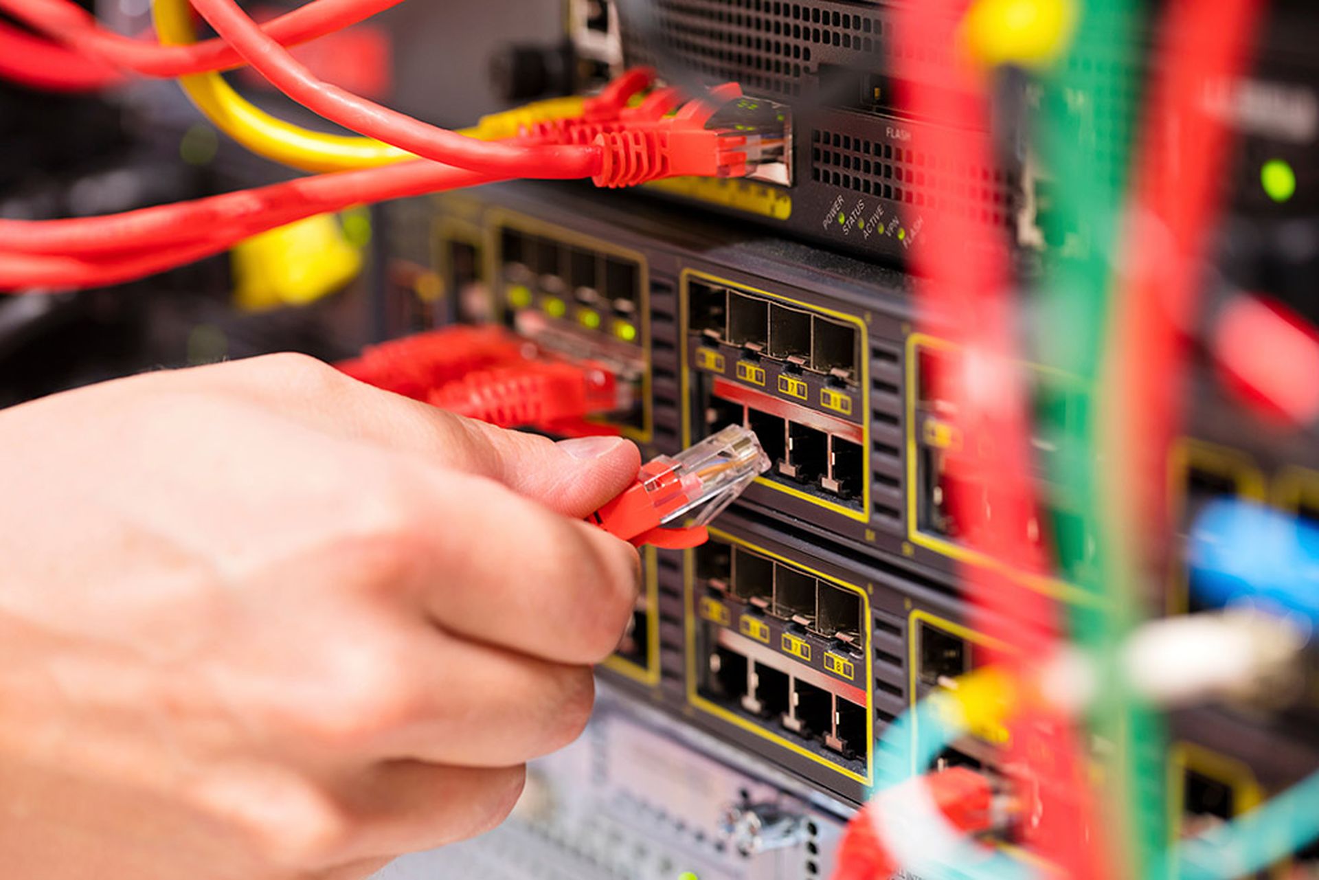 IT technician or engineer connects a gigabit network cable into switch in datacenter