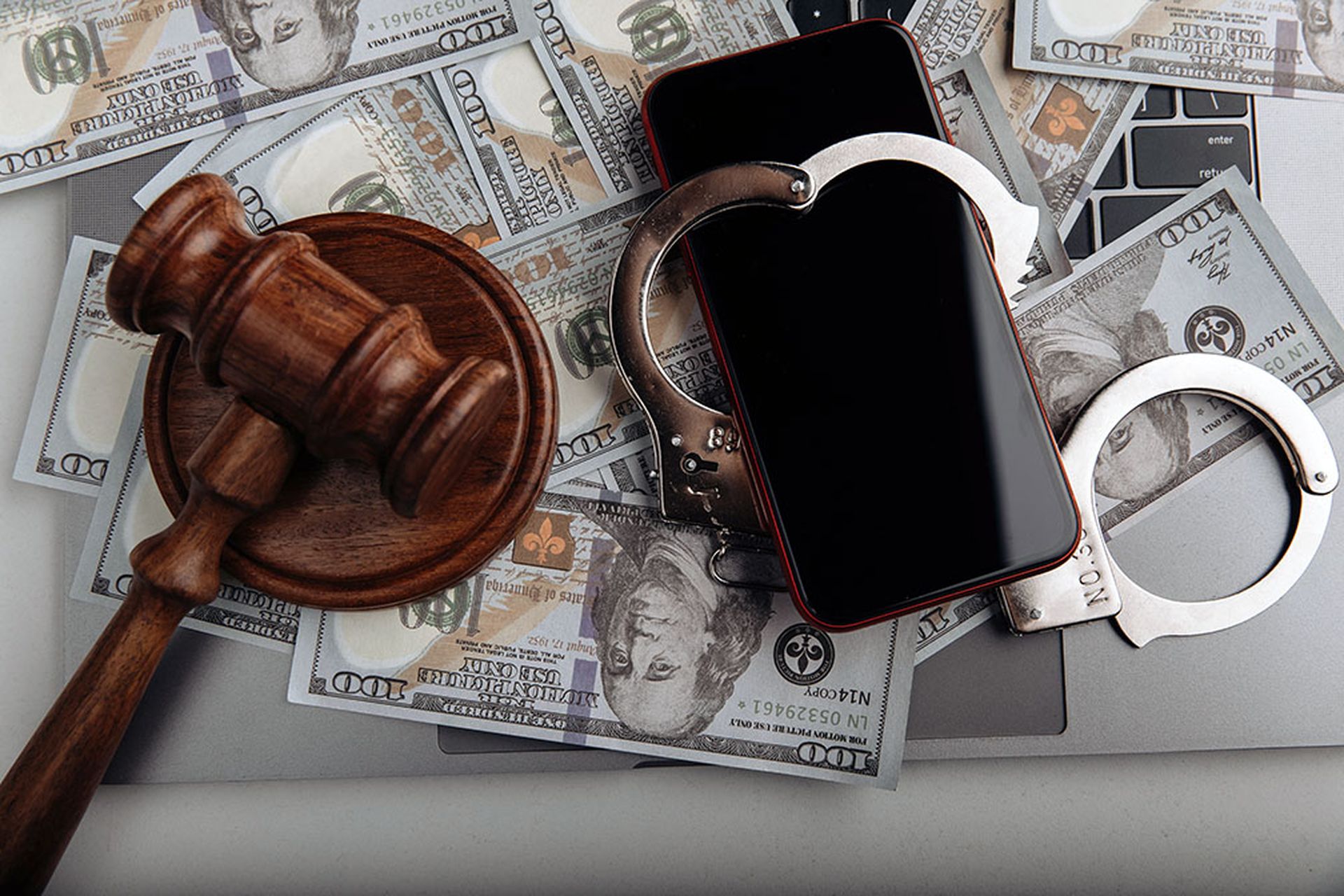 Smartphone with handcuff on a dollar banknotes and judge gavel. Cyber crime and law concept.