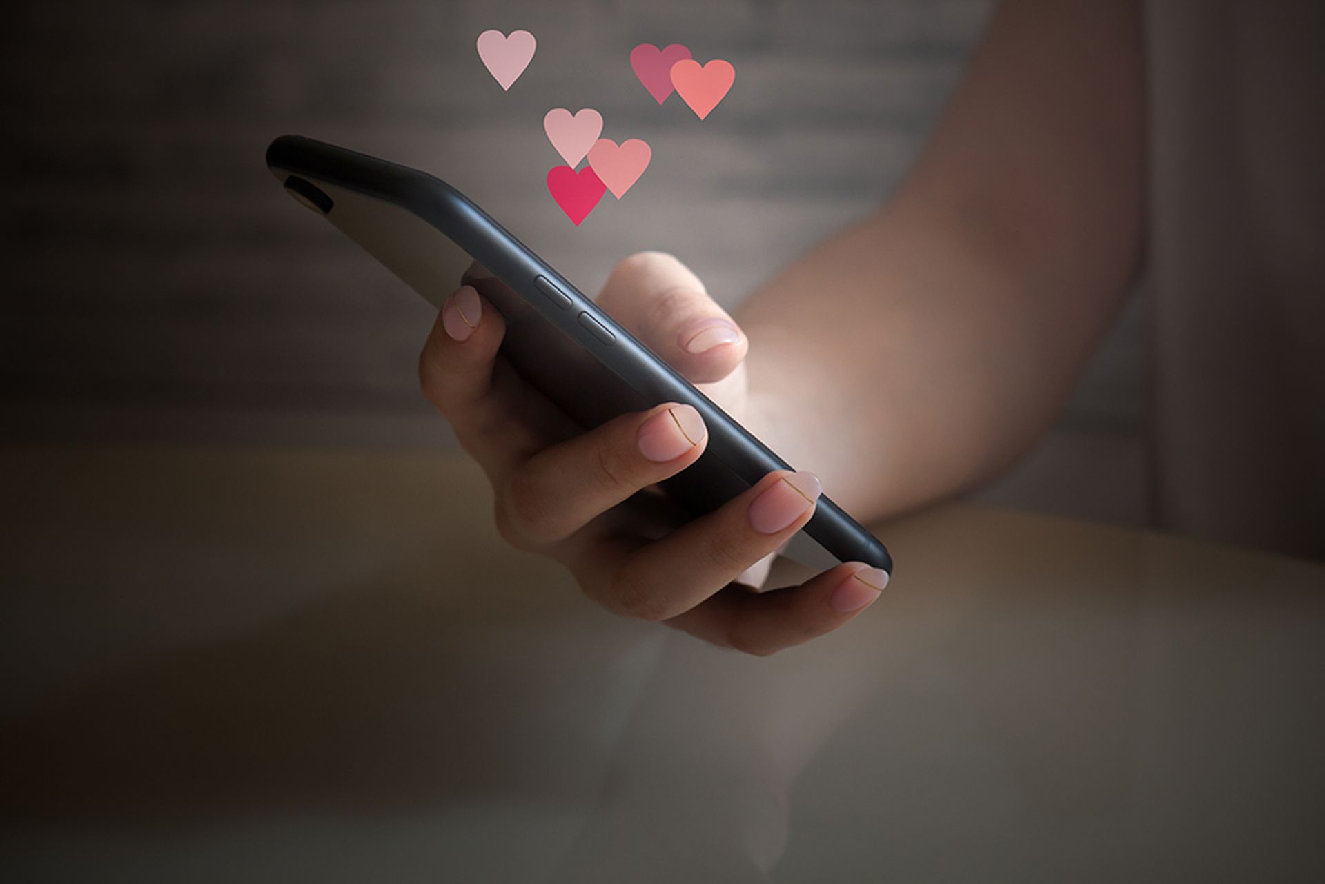 Woman hand holding mobile phone with glowing screen with different virtual hearts