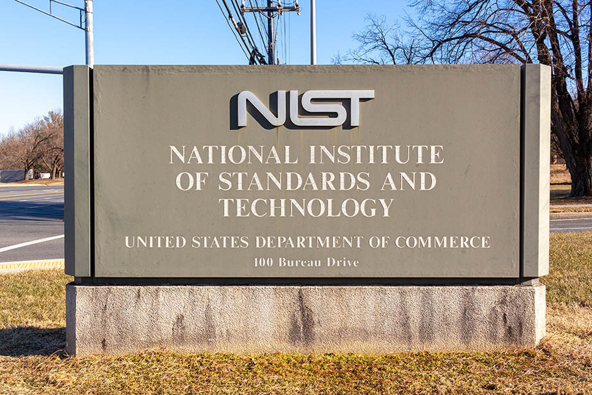 A sign for the National Institute of Standards and Technology is seen in the sunlight at an intersection.
