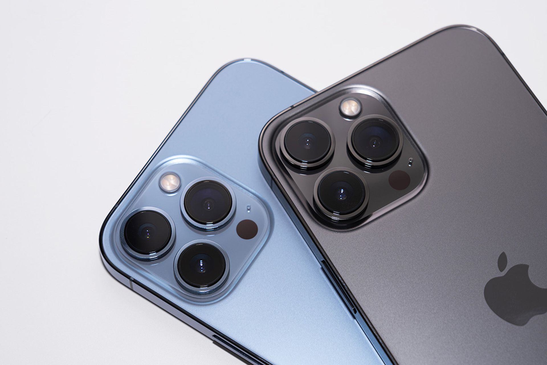 Close up the triple-lens camera on the iPhone 13 Pro Max Seirra Blue and Graphite Color on white background.