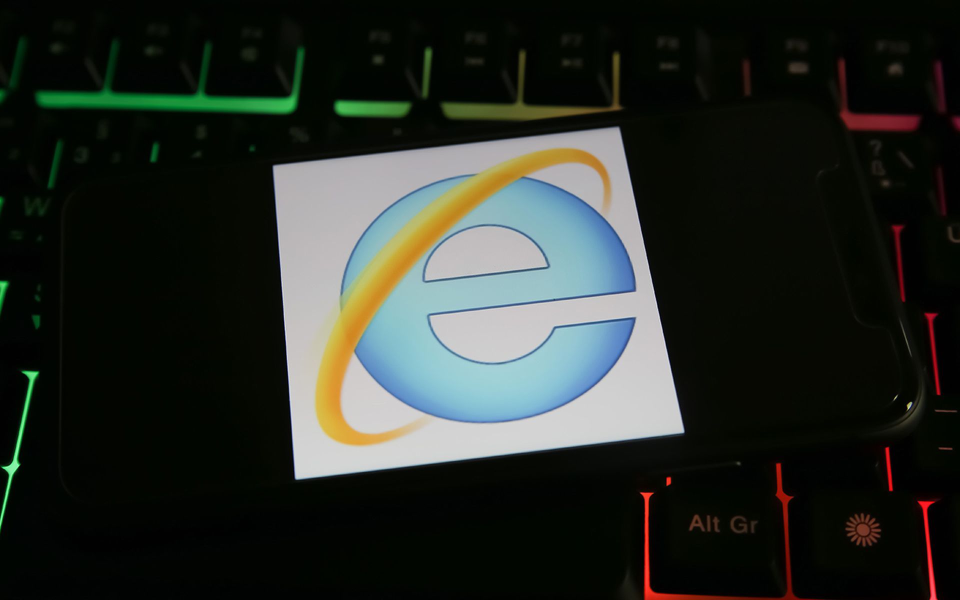Closeup of mobile phone screen with logo lettering of microsoft internet explorer browser on computer keyboard