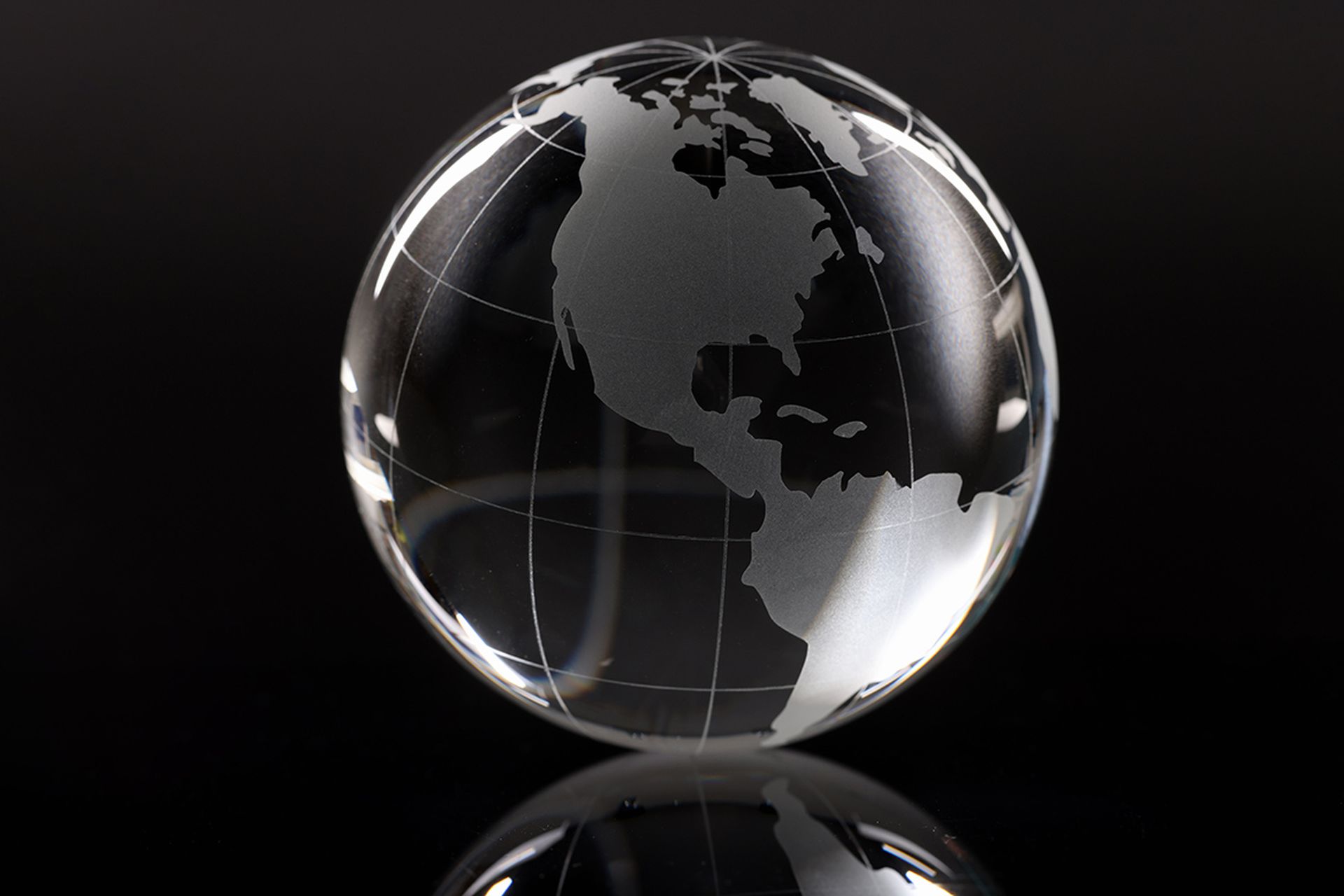 Closeup of glass globe on black background. Screensaver for world news concept