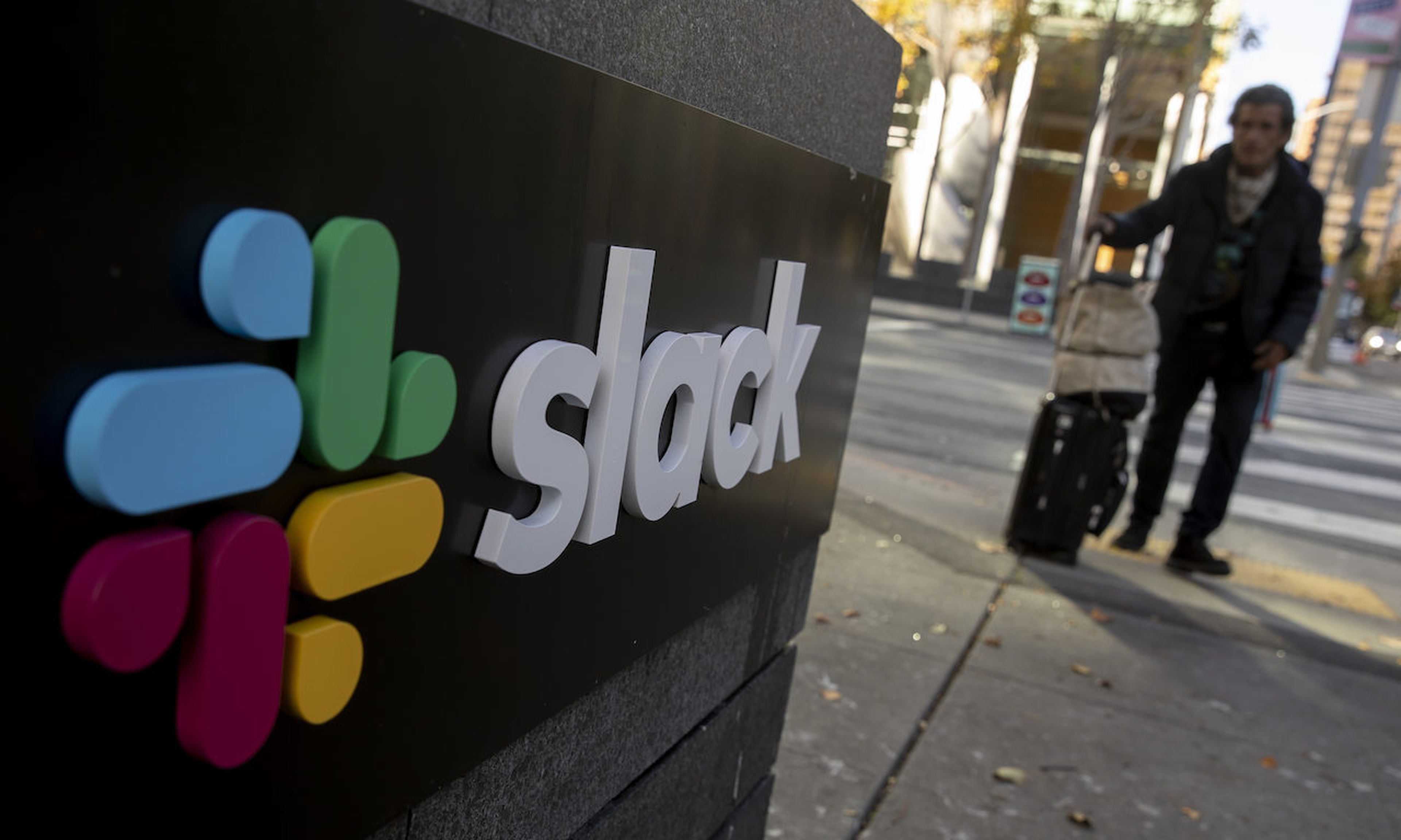 A pedestrian walks past a Slack logo outside its headquarters on December 1, 2020 in San Francisco, California. Collaborative tools proved an easy target for hackers during the pandemic. (Photo by Stephen Lam/Getty Images)