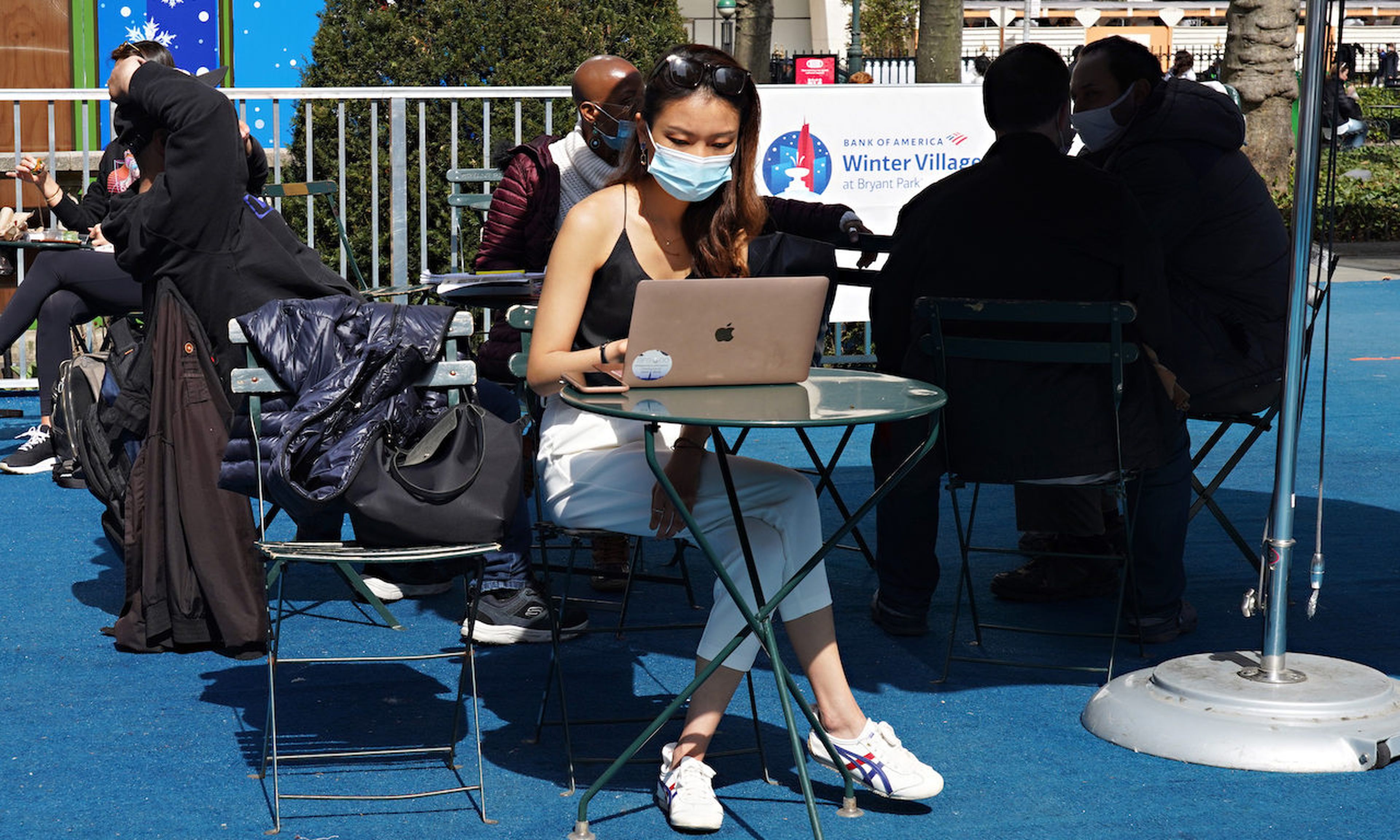 A person wearing a protective mask uses a laptop computer in Bryant Park on March 23, 2021 in New York City. (Photo by Cindy Ord/Getty Images)
