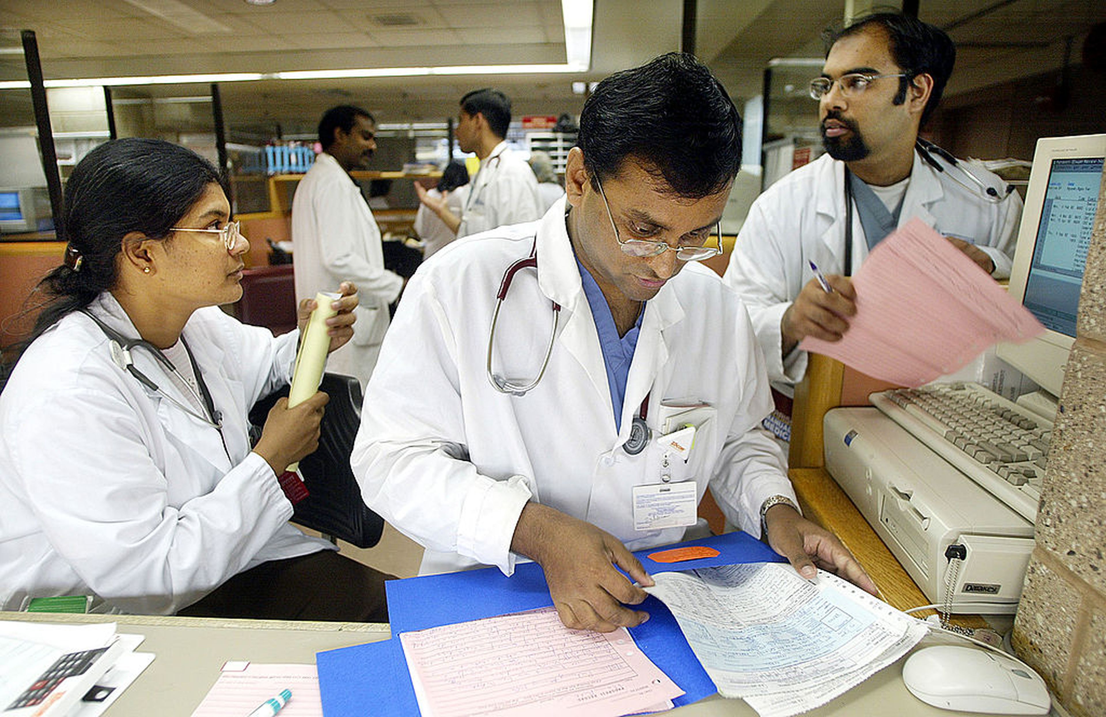 Doctors prepare paperwork in the physician consultation area of the emergency room at Coney Island Hospital Sept. 5, 2002, in New York City. (Photo by Mario Tama/Getty Images)