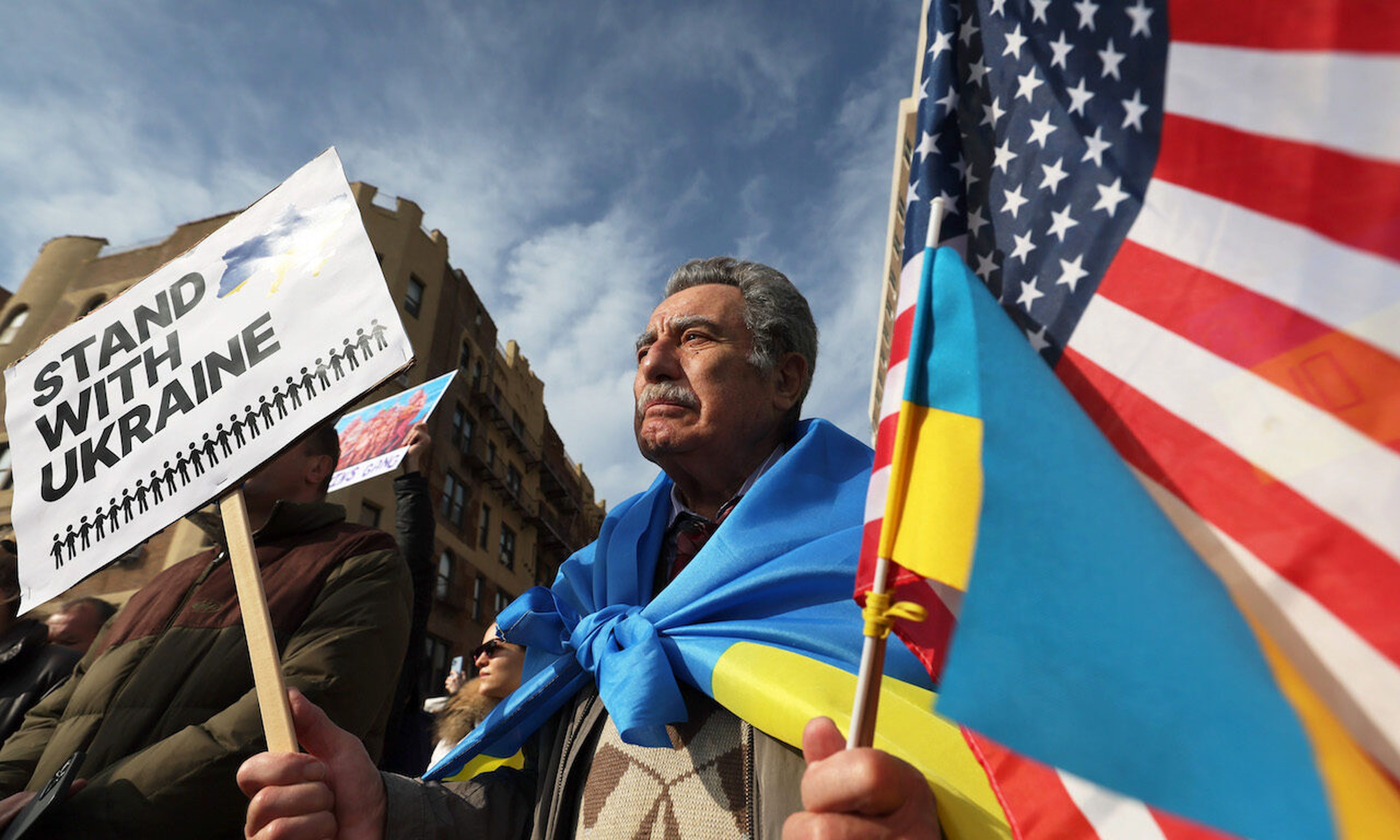 A proteter in New York holds a sign and flags as he joins others who gathered for a rally in support of Ukraine (Photo by Michael M. Santiago/Getty Images)