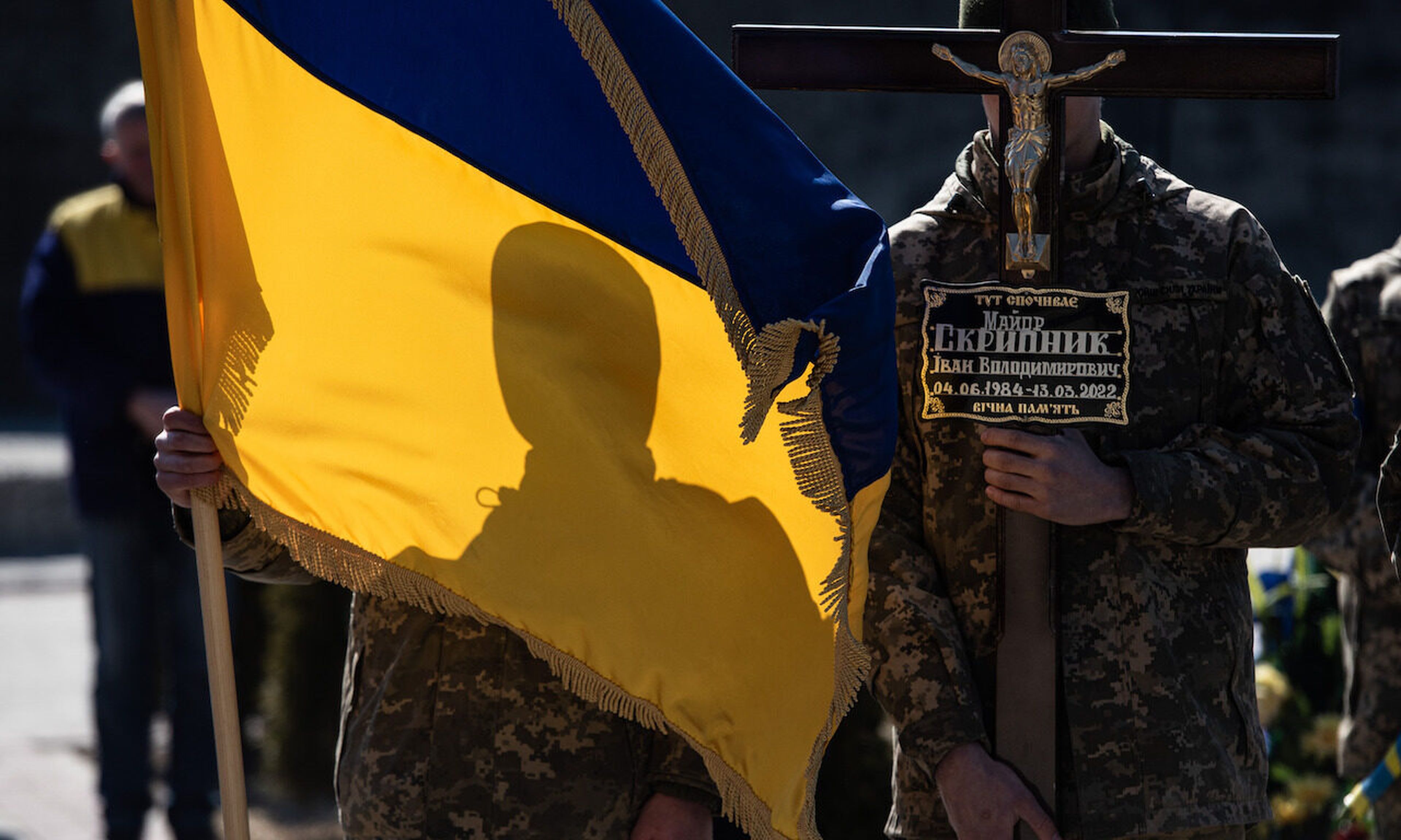 Ukrainian servicemen hold a national Ukrainian flag and a cross during the funeral ceremony on March 17, 2022 in Lviv, Ukraine. (Photo by Alexey Furman/Getty Images)
