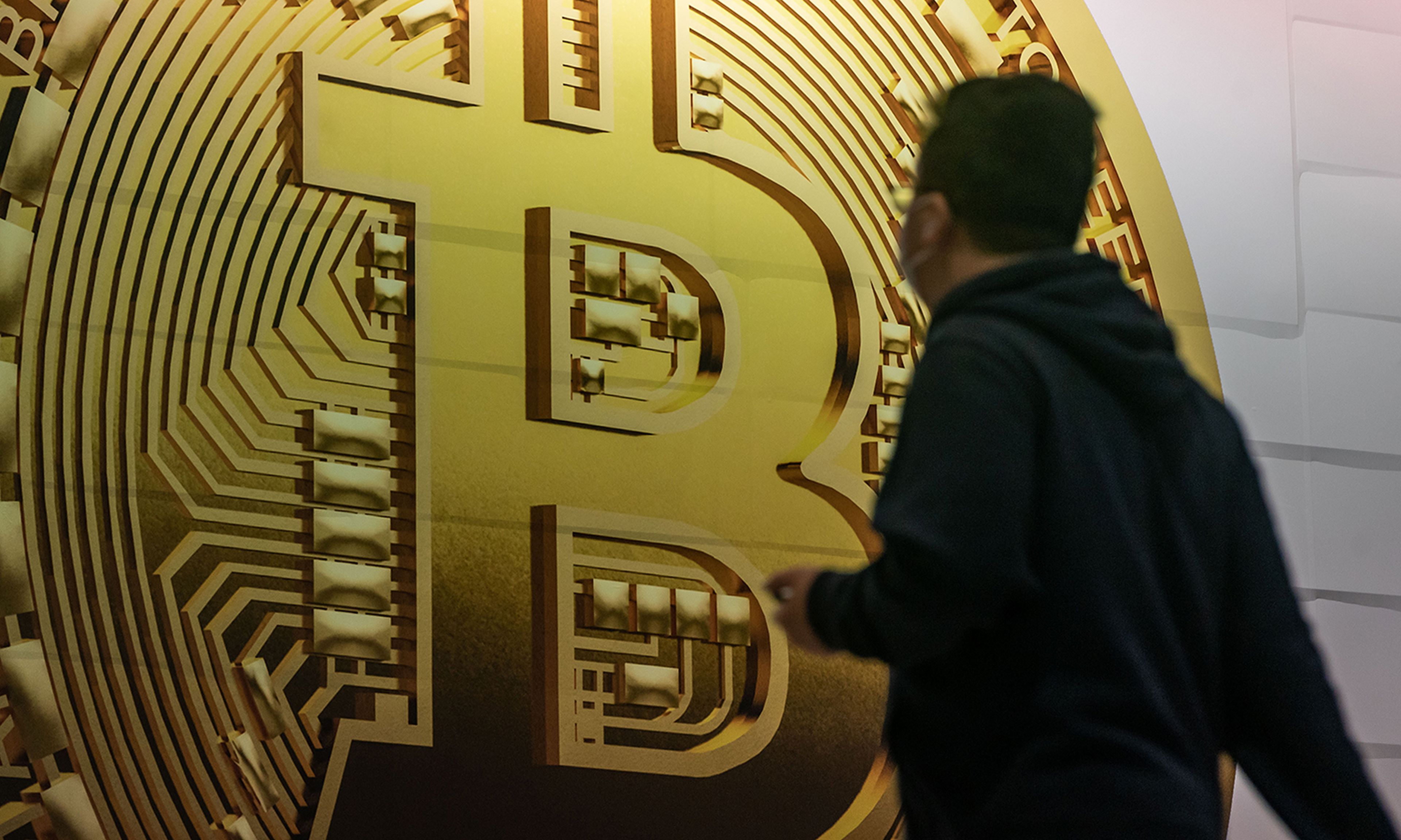 Pedestrians walk past an advertisement displaying a Bitcoin cryptocurrency token on Feb. 15, 2022, in Hong Kong. (Photo by Anthony Kwan/Getty Images)