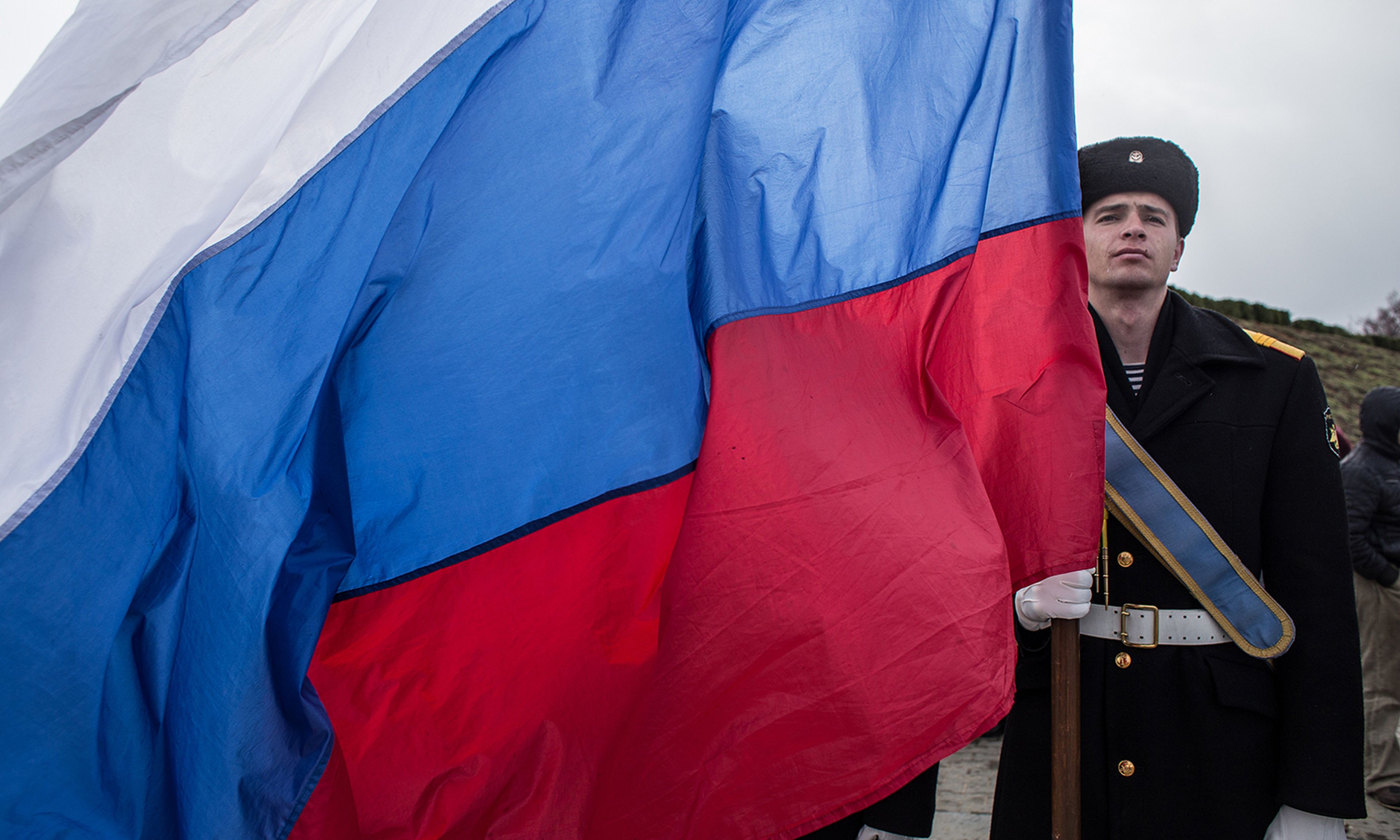 Pictured: A sailor holds a Russian flag as people celebrate the first anniversary of the signing of the decree on the annexation of the Crimea by the Russian Federation on March 18, 2015, in Sevastopol, Crimea. (Photo by Alexander Aksakov/Getty Images)
