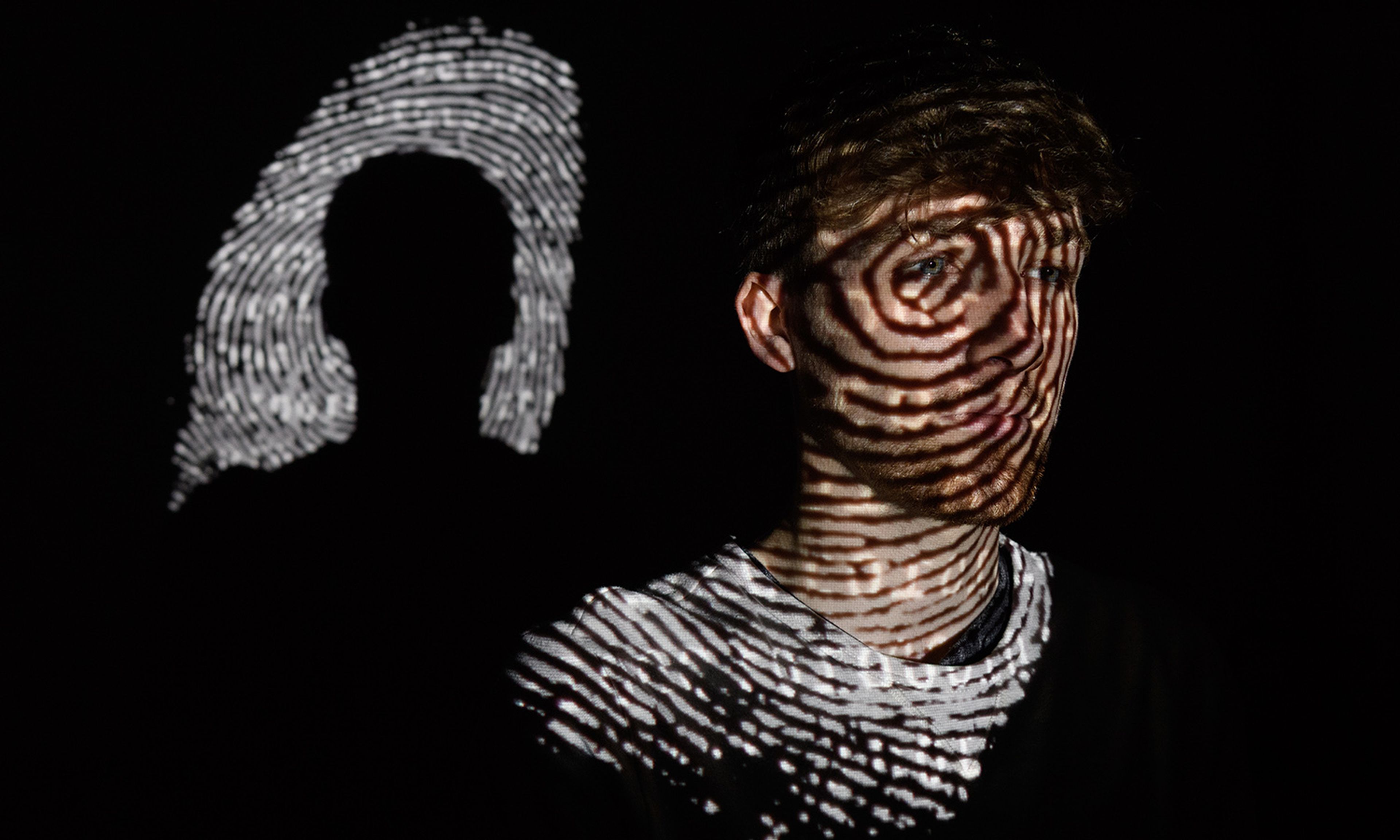 A thumbprint is projected onto a man. (Photo by Leon Neal/Getty Images)
