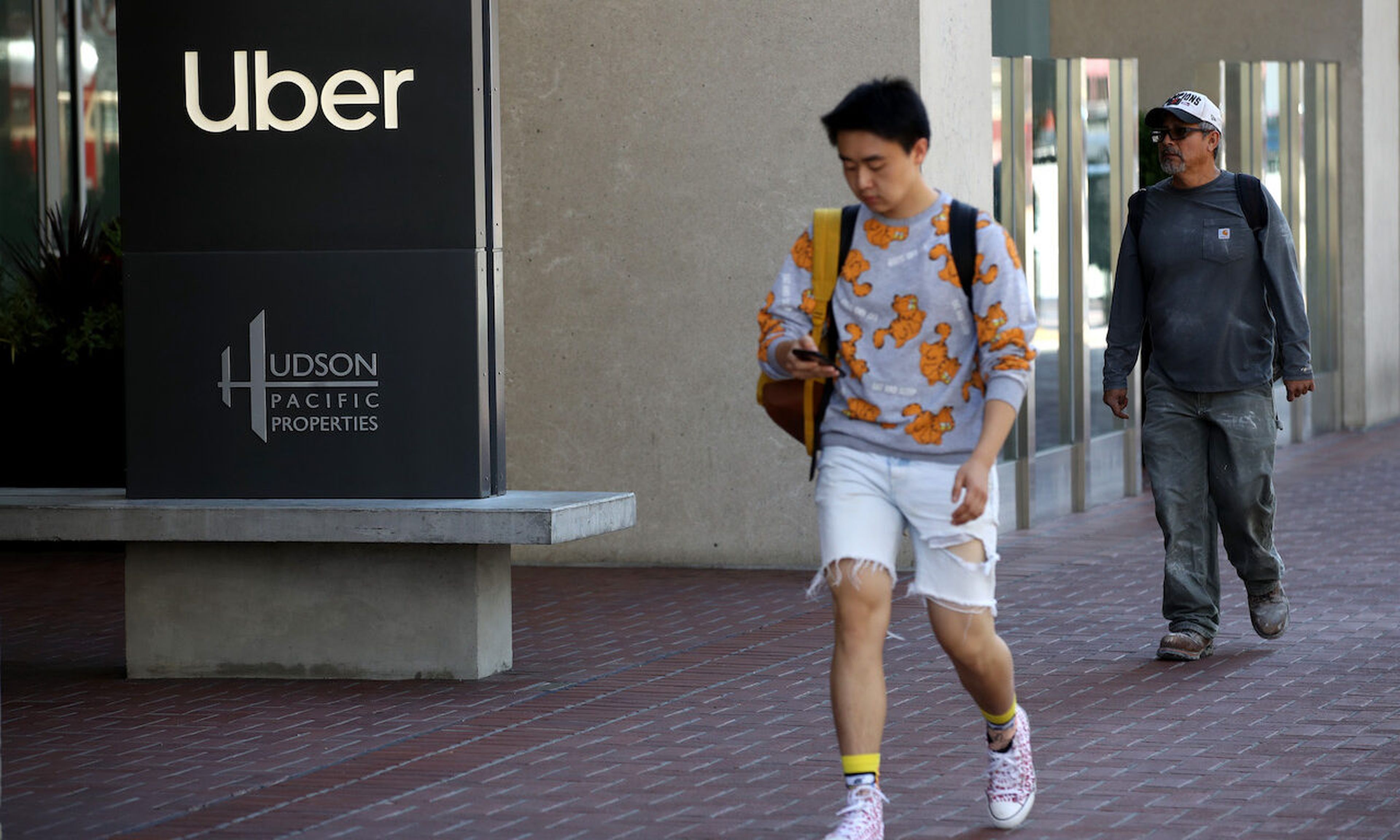 Pedestrians walk by Uber headquarters in San Francisco, California. Uber suffered a recent breach, likely the result of an intruder gaining initial access by contacting an Uber employee over WhatsApp. (Photo by Justin Sullivan/Getty Images)