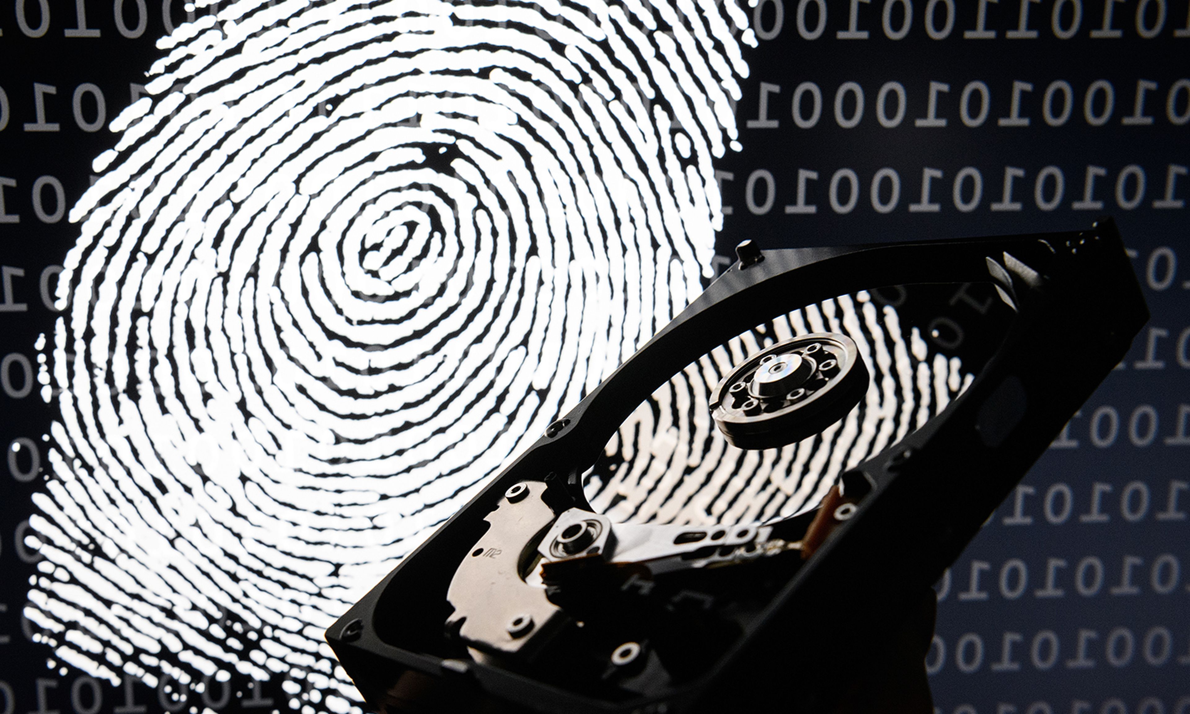 A hard drive is seen in the light of a projection of a thumbprint.