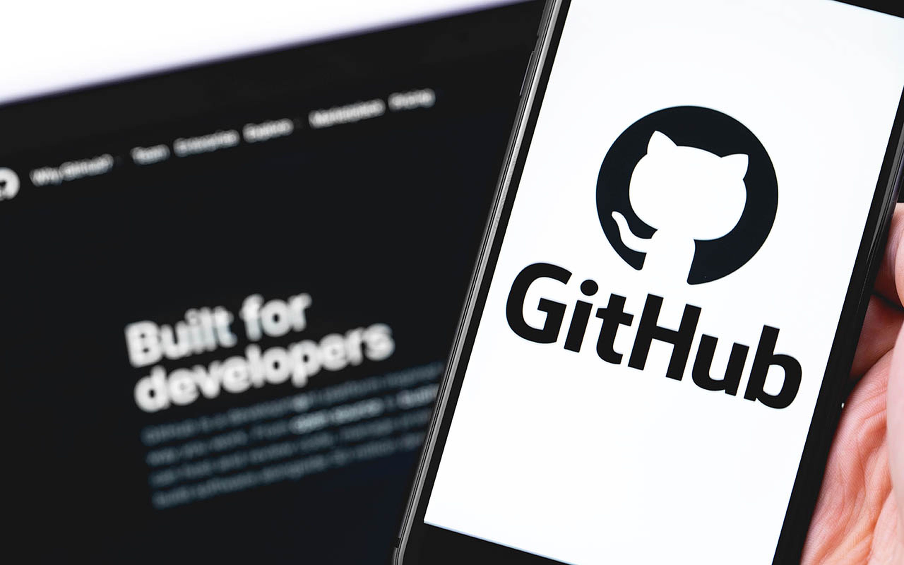 GitHub logo on the screen smartphone and notebook closeup.