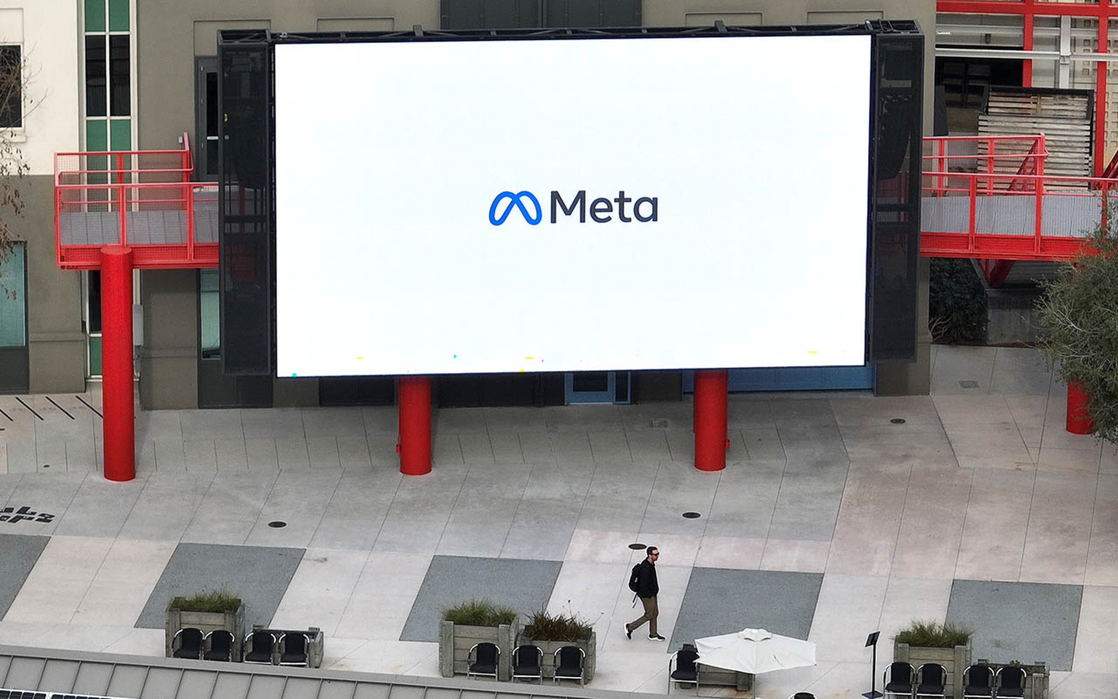 A worker walks by a video monitor on the Meta campus.