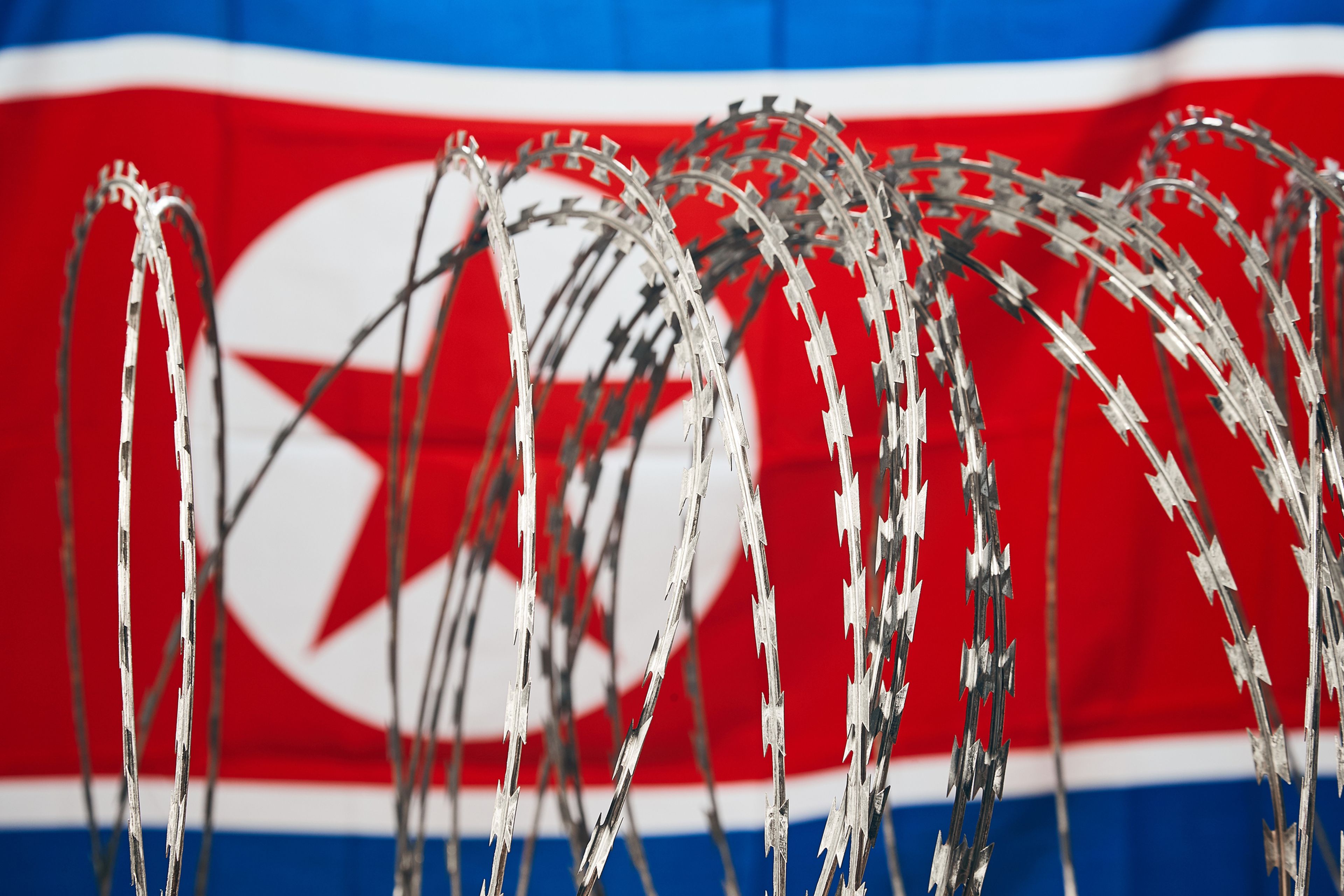 Barbed wire barricade seen in front of the national flag of North Korea
