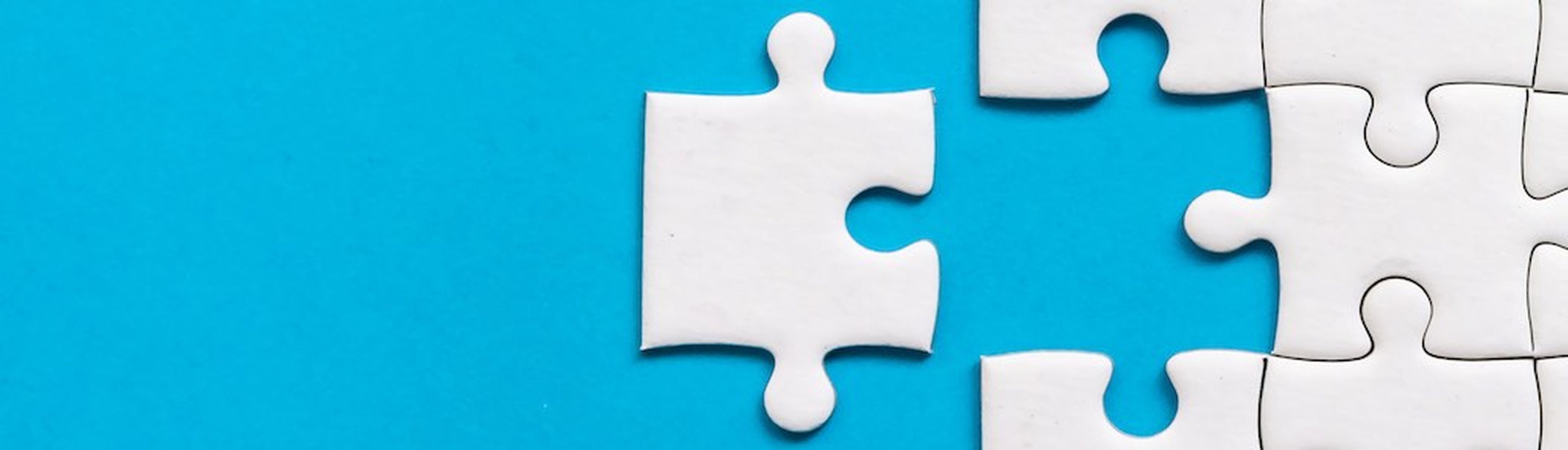 White jigsaw puzzle on blue background. Team business success partnership or teamwork