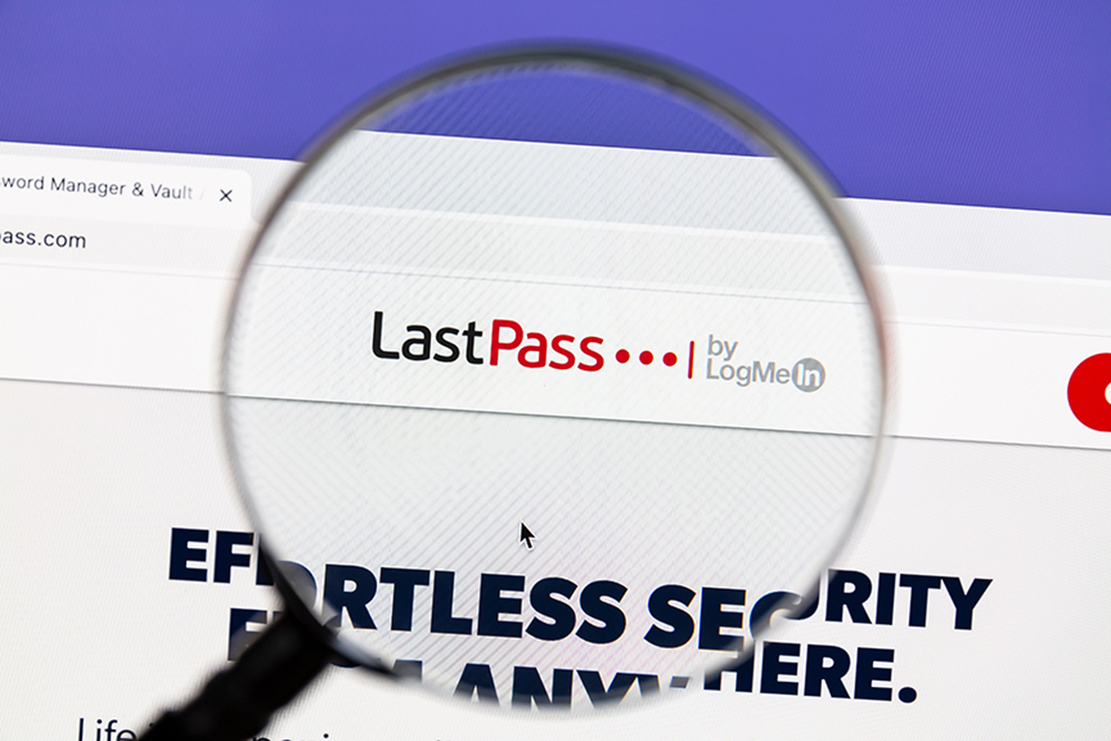 LastPass website under a magnifying glass. LastPass is a freemium password manager that stores encrypted passwords online.