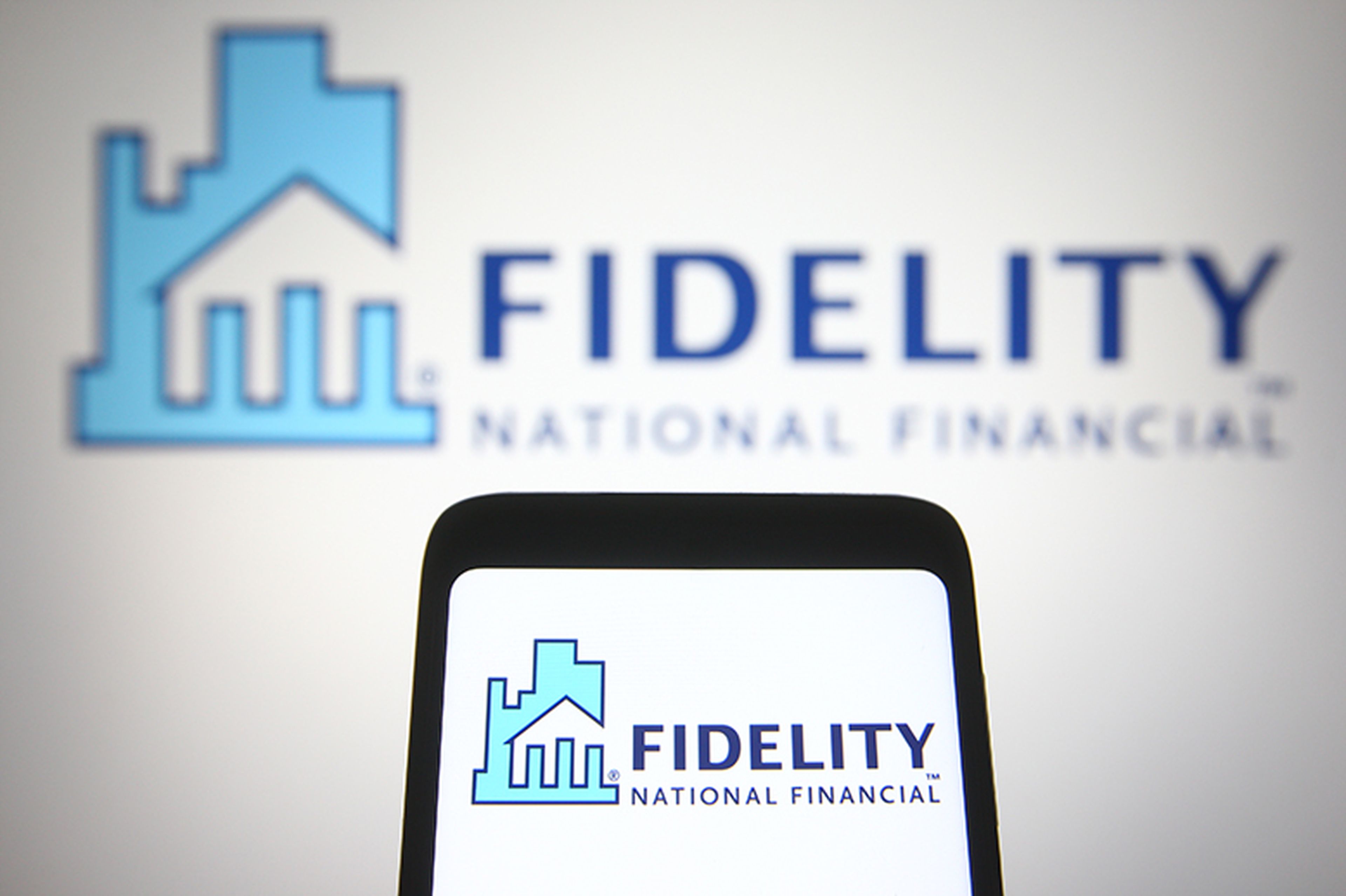 A Fidelity National Financial (FNF) logo is seen on a smartphone and a PC screen.