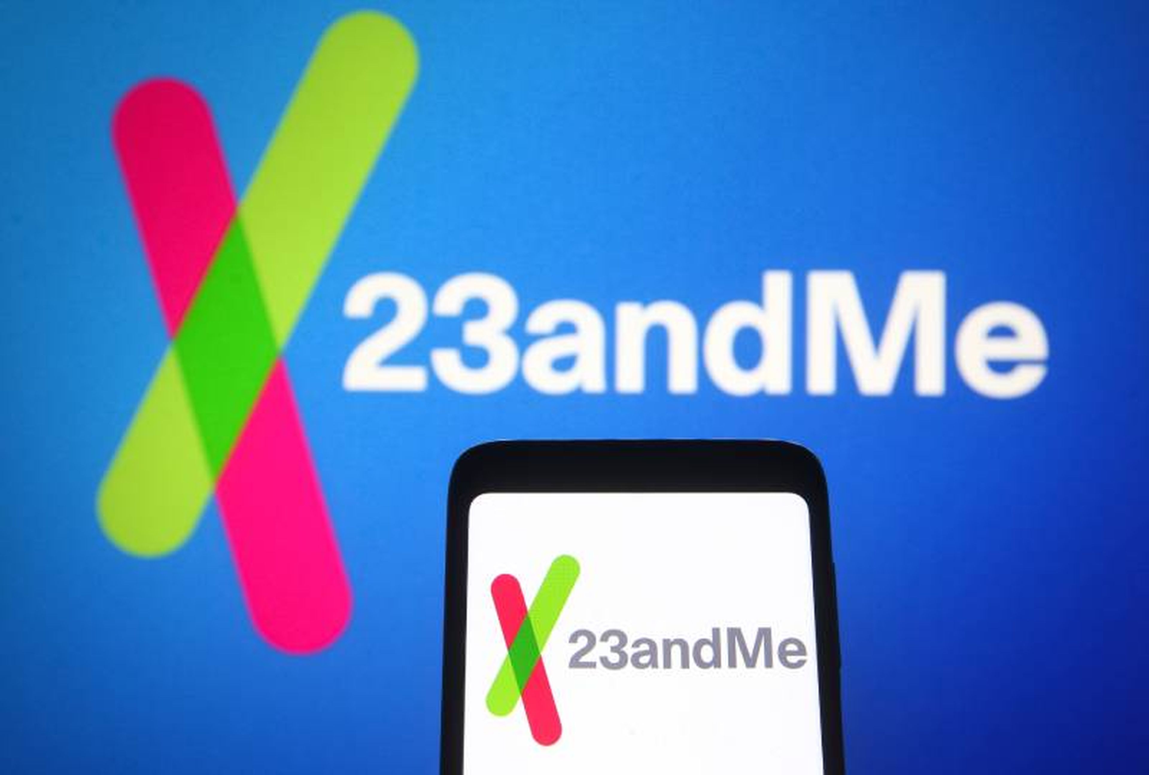 In this photo illustration, 23andMe logo of a biotechnology company is seen on a smartphone and a pc screen in the background.