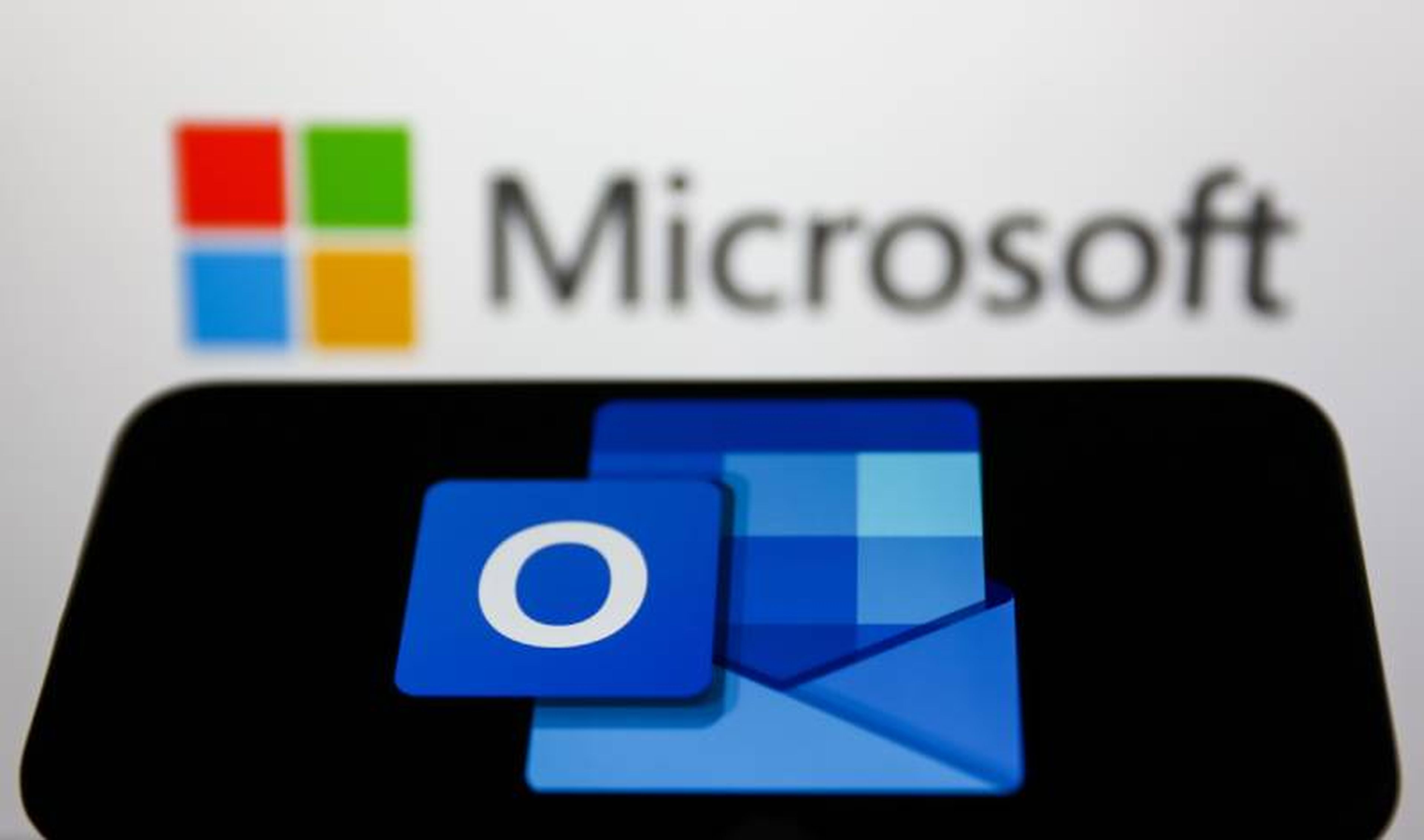 Microsoft Outlook logo displayed on a phone screen and Microsoft logo displayed on a screen in the background are seen in this illustration photo taken in Krakow, Poland on May 26, 2022. (Photo Illustration by Jakub Porzycki/NurPhoto via Getty Images)