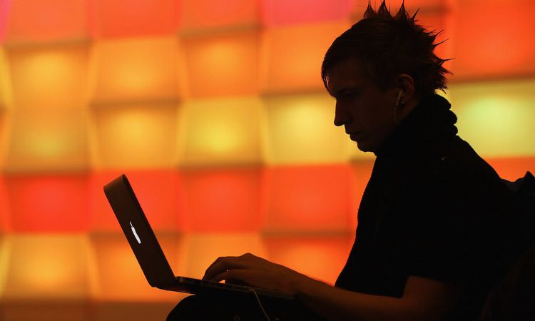 A participant sits with a laptop computer as he attends an annual conference of computer hackers in 2010. (Photo by Sean Gallup/Getty Images)